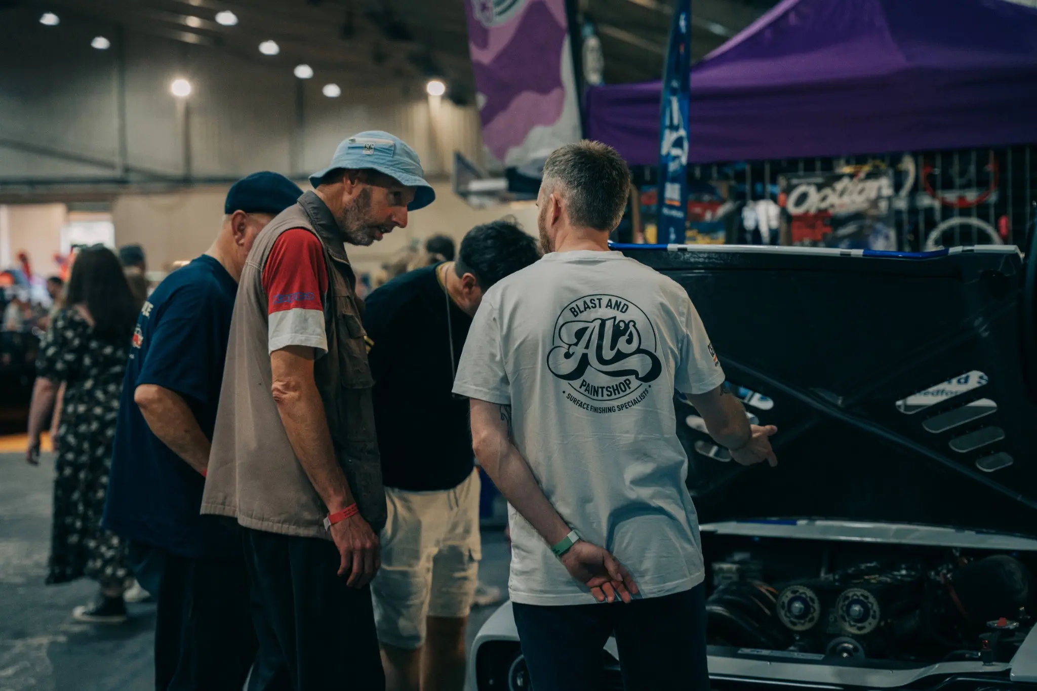 An AL's Blast and Paintshop specialist discussing a vehicle at an industry event